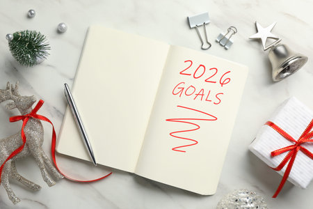 New 2026 Year Goals. Inscription in notebook on white marble table with festive stuff, top view