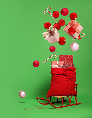 Christmas balls, gift boxes and candy canes into bag on green backgroundの写真素材