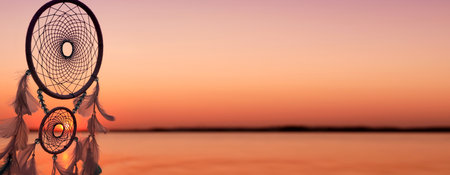 Dream catcher with feathers against sea at sunset. Banner designの写真素材