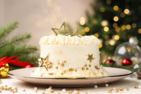 Delicious cake with Christmas decor on white table against blurred lights, closeupの写真素材