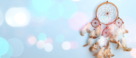 Dream catcher with feathers on light blue background, bokeh lights. Banner designの写真素材