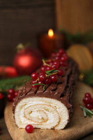 Delicious Yule log (traditional Christmas cake) with redcurrant on wooden table, closeupの写真素材