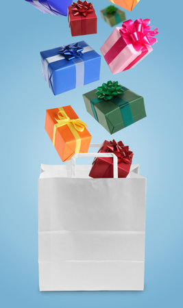 Many gift boxes falling into paper bag on light blue backgroundの写真素材