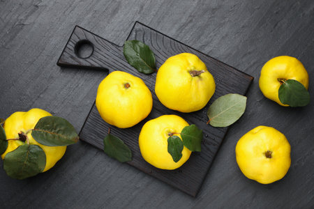 Ripe quinces and green leaves on black textured table, flat layの写真素材