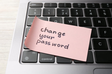 Note with phrase Change your password and laptop on white wooden desk, closeupの写真素材