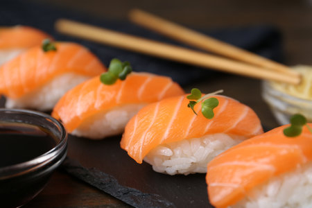 Delicious nigiri sushi with salmon, microgreens and soy sauce on wooden table, closeupの写真素材