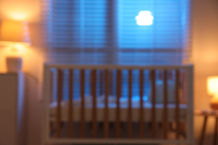 Blurred view of stylish baby's room with crib, dresser, lamps and decor at night. Interior designの写真素材