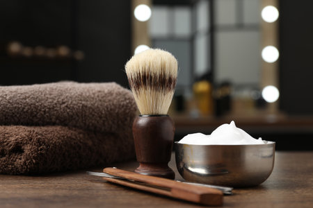 Shaving brush, foam, straight razor and towels on wooden table in barbershop, closeupの写真素材