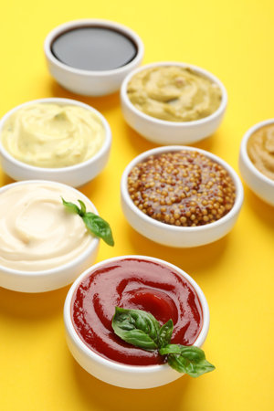 Different sauces and herbs on yellow background, closeupの写真素材