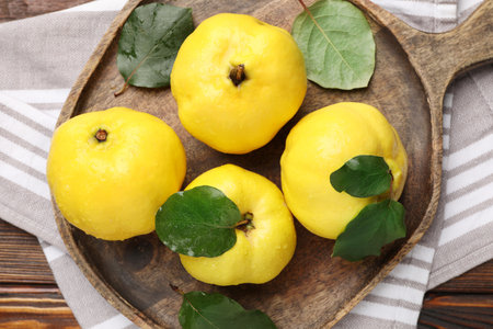 Fresh ripe quinces with leaves on wooden table, top viewの写真素材