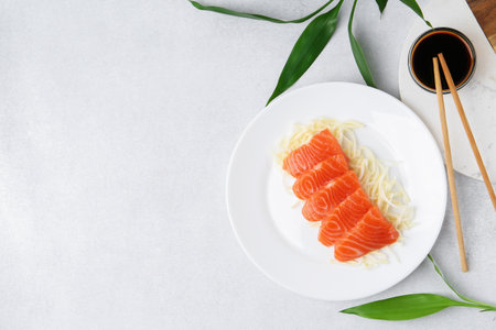 Fresh salmon sashimi with sliced radish and soy sauce on light gray table, flat lay. Space for textの写真素材