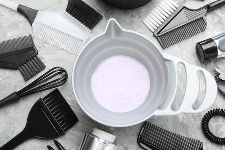 Hair dyeing product in bowl and different hairdresser's tools on light gray table, flat layの写真素材