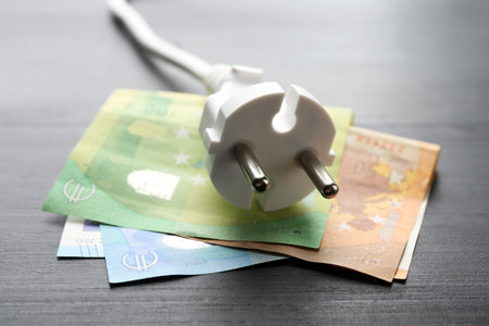 Electrical wire with plug and euro banknotes on black wooden table, closeupの写真素材