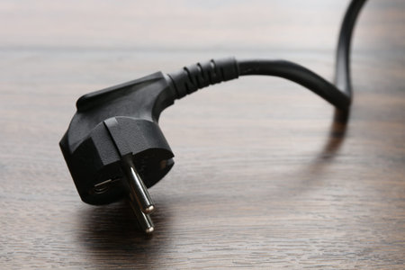 Electrical wire with plug on wooden table, closeup