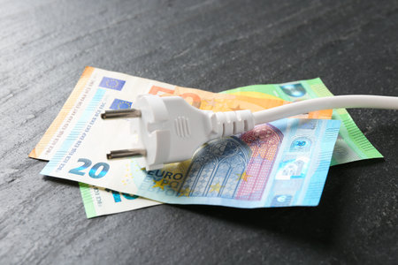 Electrical wire with plug and euro banknotes on black table, closeupの写真素材