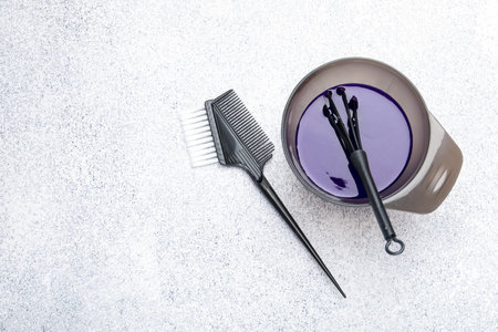 Hair dyeing product in bowl and hairdresser's tools on light gray table, flat lay. Space for textの写真素材