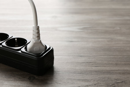 Power strip with electrical plug on wooden table, closeup. Space for textの写真素材