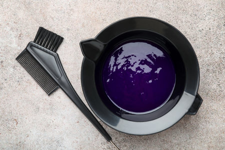 Hair dyeing product in bowl and brush on light gray table, top viewの写真素材