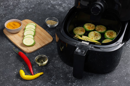 Air fryer with grilled vegetables and spices on gray table, closeupの写真素材