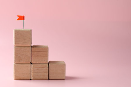 Winner. Stacked cubes with small flag on pink background, space for textの写真素材