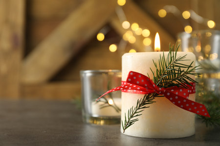 Burning candle with pinecone scent on black table, closeup. Space for textの写真素材