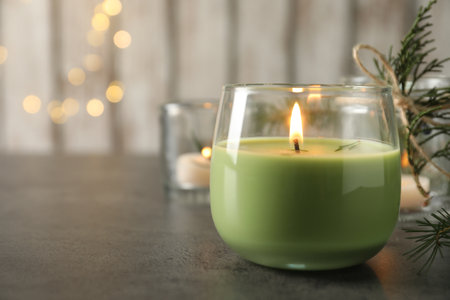 Burning candle with pinecone scent on black table, closeup. Space for textの写真素材
