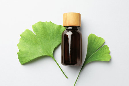 Ginkgo biloba leaves and bottle on light gray background, flat layの写真素材
