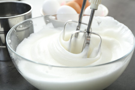 Beating egg whites with mixer at gray table, closeupの写真素材