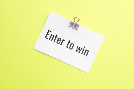 Paper note with phrase Enter To Win on yellow background, top viewの写真素材