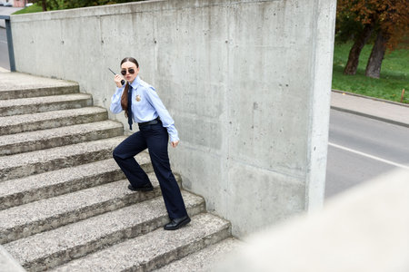 Police officer with radio on steps outdoors. Space for text