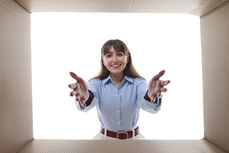 Woman looking into cardboard box against white background, view from inside packageの写真素材
