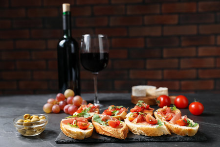 Delicious bruschettas with prosciutto served on black table. Space for textの写真素材