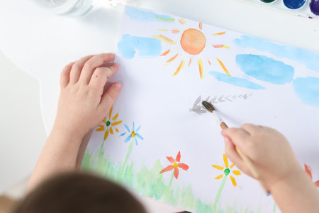 Little boy with brush drawing at white table indoors, above viewの写真素材