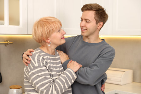 Mother and son hugging each other in kitchenの写真素材