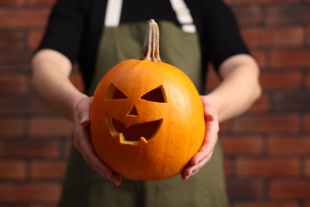 Halloween celebration. Woman with carved pumpkin against brick wall, closeupの写真素材