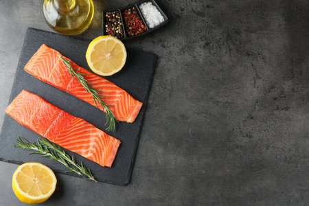 Pieces of salmon fillet and spices on gray table, flat lay.の写真素材