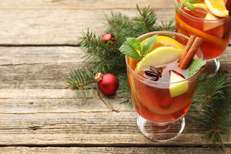 Tasty punch drink in glasses, spices and Christmas decor on wooden table, closeup. Space for textの写真素材