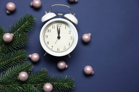 Alarm clock, fir tree branches and baubles on blue background, flat lay with space for text. New...