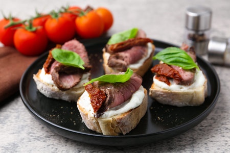 Bruschettas with roast beef served on gray table, closeup