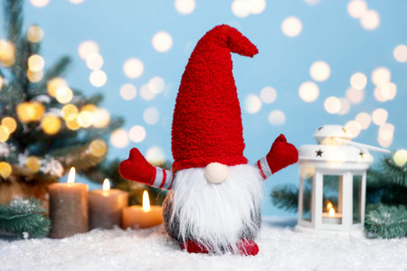 Funny Christmas gnome and festive decor on artificial snow against light blue background with blurred lights. Bokeh effectの写真素材