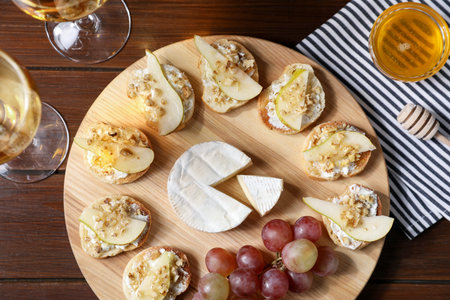 Delicious bruschettas served with camembert, grapes on wooden table, flat lay