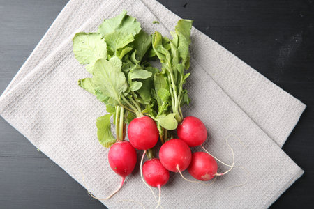 Fresh ripe radishes on black wooden table, top view