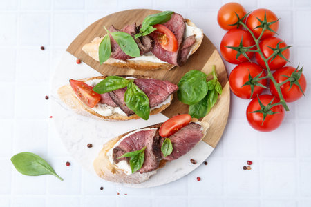 Delicious bruschettas with beef served on white tiled table, flat layの写真素材