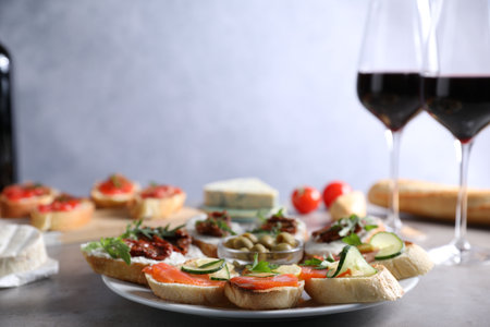 Different tasty bruschettas and red wine on gray textured table, closeupの写真素材