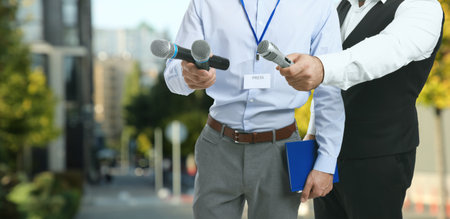 Journalists with microphones and notebook outdoors, closeup.の写真素材