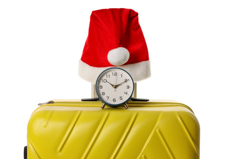 Stylish suitcase with Santa hat and alarm clock isolated on white. Christmas vacationの写真素材