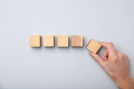 Man with wooden cubes on light background, top viewの写真素材