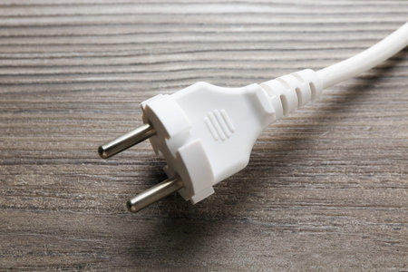 Electrical wire with plug on wooden table, closeup
