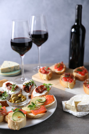 Different tasty bruschettas and red wine on gray textured table, closeupの写真素材