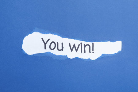 Phrase You Win! on white background, view through hole in torn blue paperの写真素材